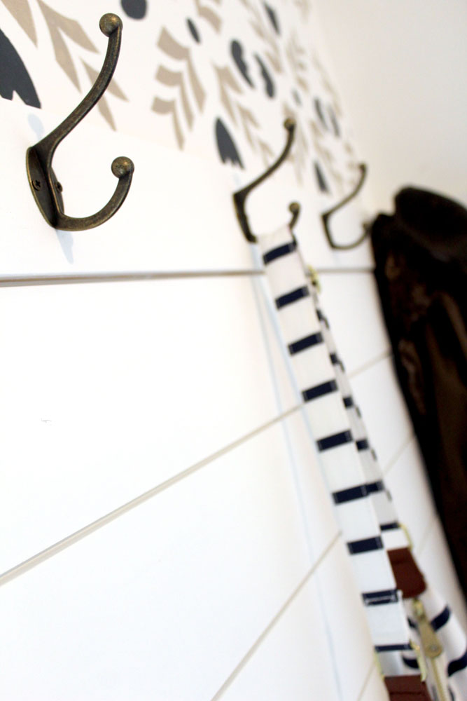 Mudroom entryway area hooks on shiplap wall with stencils