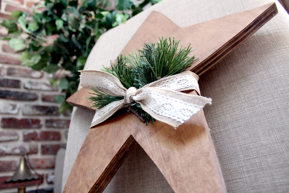 Wooden Christmas star with ribbon and greenery ready to hang on the door