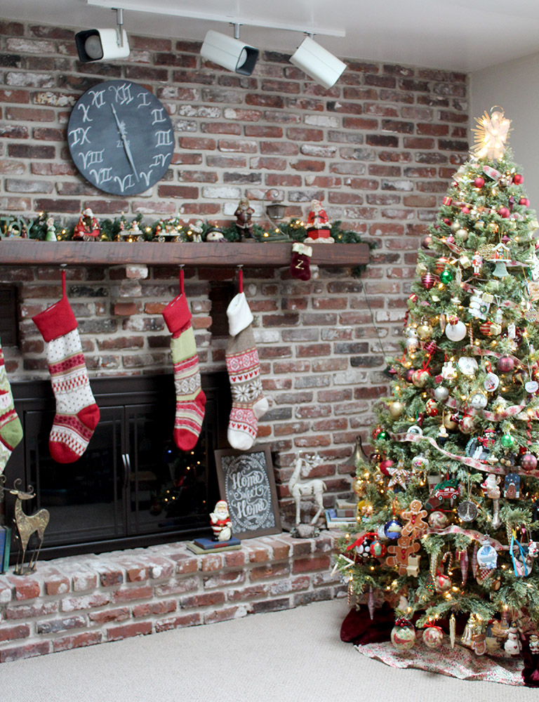 Family room with brick mantle wall decorated for the holidays with full size ornament filled tree