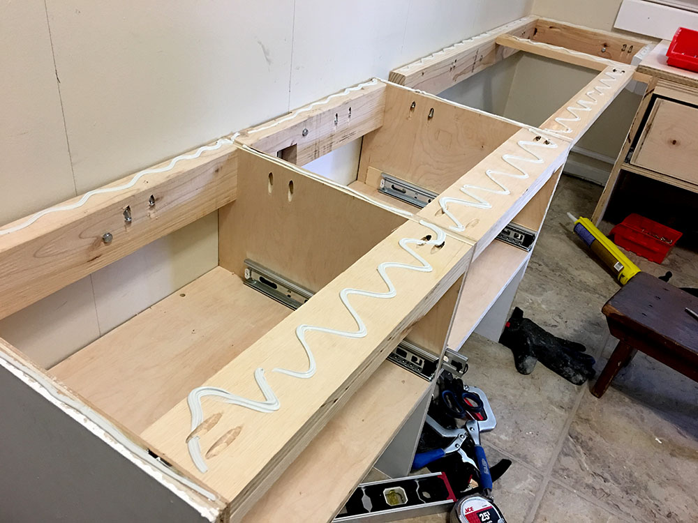 Attaching the cubby storage to the benchtop with construction adhesive for an entryway bench makeover